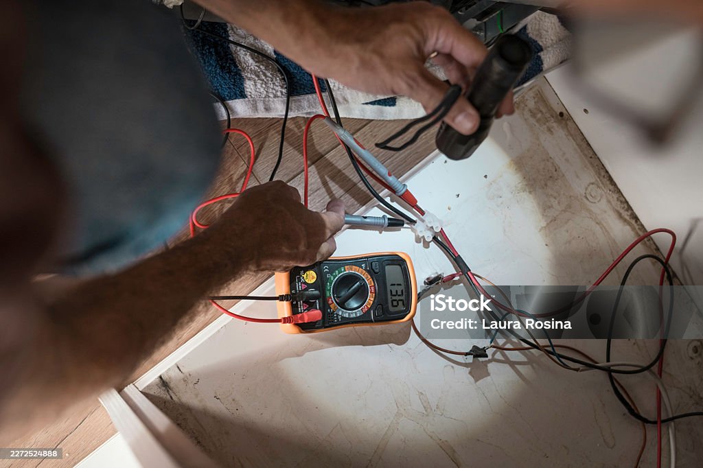 Technician testing boat wiring with a digital multimeter